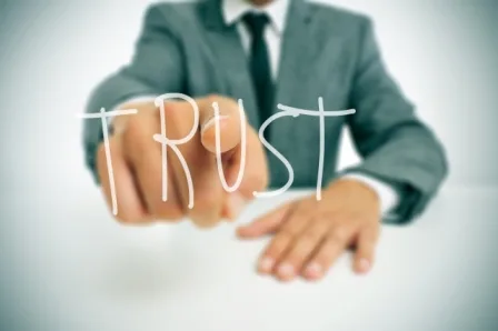 מנהל השקעות בחליפה מצביע עם המילה TRUST על התמונה במכללת אורין שפלטר
